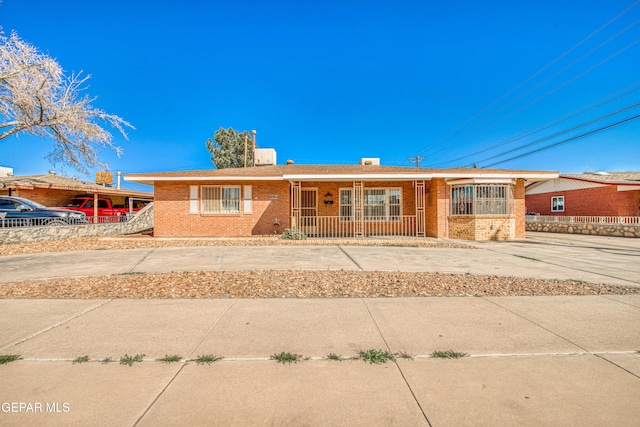 single story home featuring brick siding and a porch