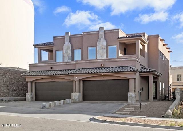 view of front of house with driveway, an attached garage, a tile roof, and stucco siding