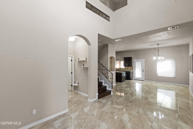 foyer entrance featuring arched walkways, a towering ceiling, visible vents, baseboards, and marble finish floor