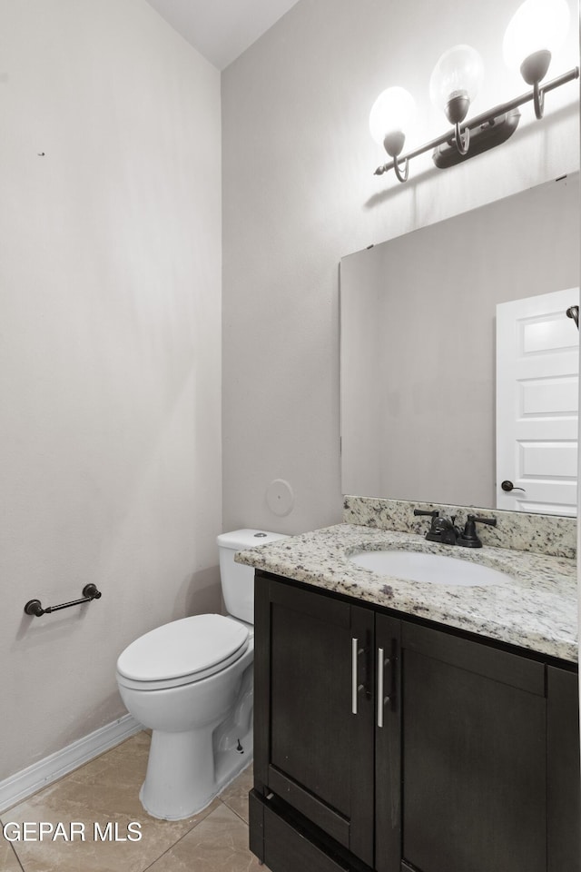 half bathroom featuring toilet, baseboards, and vanity