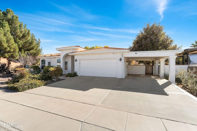 mediterranean / spanish-style home featuring driveway, a tiled roof, a carport, and stucco siding