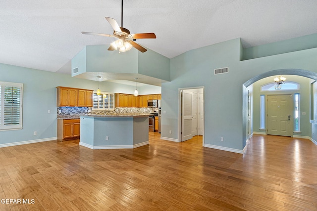 kitchen with appliances with stainless steel finishes, visible vents, brown cabinetry, and open floor plan