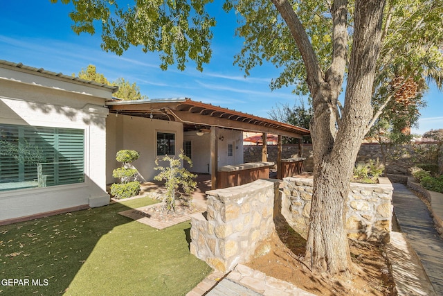 rear view of house featuring a patio, a fenced backyard, a ceiling fan, a yard, and stucco siding