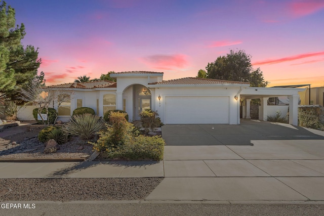 mediterranean / spanish house with stucco siding, concrete driveway, and a tiled roof