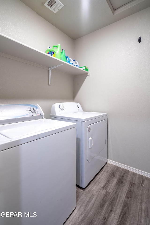 clothes washing area with visible vents, light wood-type flooring, laundry area, independent washer and dryer, and baseboards