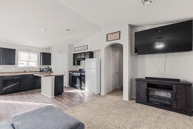 kitchen featuring black dishwasher, arched walkways, range with gas stovetop, freestanding refrigerator, and dark cabinetry