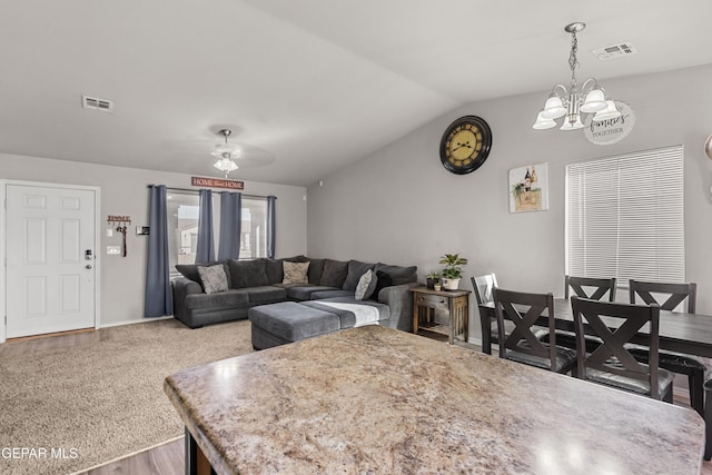 living room featuring lofted ceiling, an inviting chandelier, visible vents, and wood finished floors