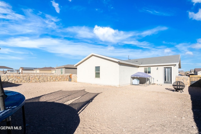 rear view of house with a patio, a trampoline, a fenced backyard, and stucco siding