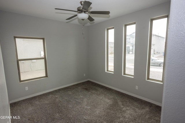 spare room featuring a ceiling fan, a wealth of natural light, carpet flooring, and baseboards