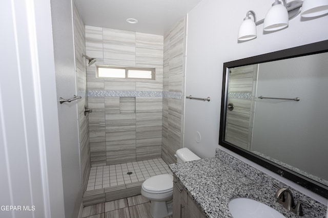 full bath featuring tiled shower, vanity, and toilet