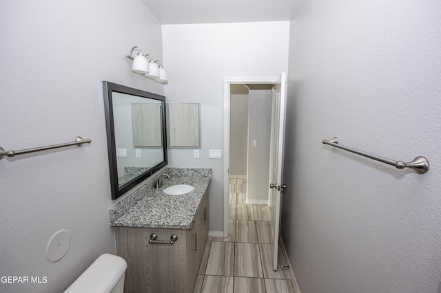 half bathroom with toilet, baseboards, and vanity