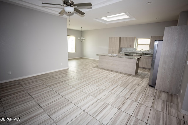 kitchen featuring a skylight, a sink, freestanding refrigerator, a center island, and modern cabinets