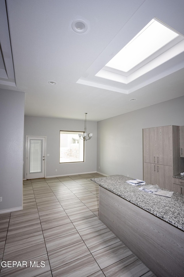 interior space featuring a skylight, baseboards, and a notable chandelier