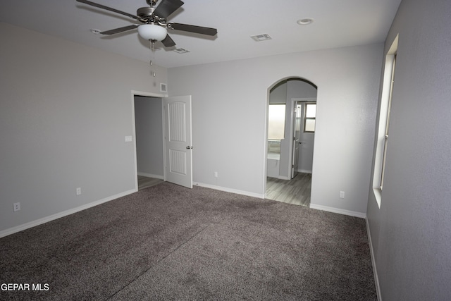 unfurnished bedroom with baseboards, visible vents, arched walkways, ensuite bath, and carpet floors