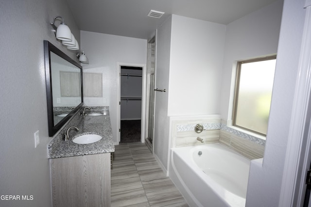 full bath featuring a walk in closet, visible vents, a sink, and a bath