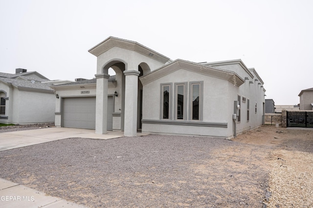 view of front of home featuring concrete driveway, an attached garage, fence, and stucco siding