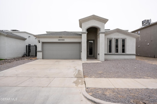 view of front facade with cooling unit, driveway, an attached garage, and stucco siding