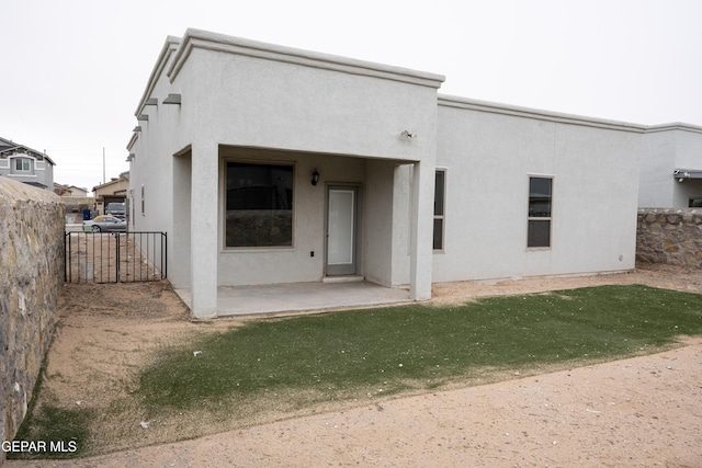 rear view of property with a patio area, fence, and stucco siding