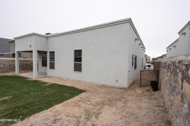 back of property featuring a patio, a yard, fence, and stucco siding