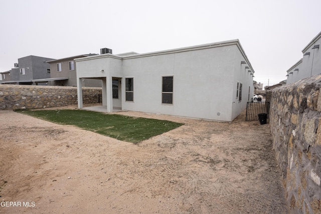 rear view of property featuring a patio, fence, and stucco siding