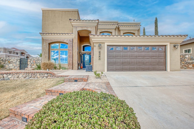 view of front of property featuring driveway, an attached garage, a tile roof, and stucco siding