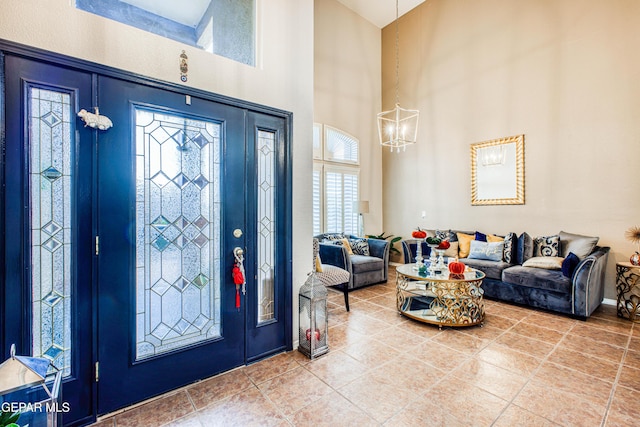 foyer featuring tile patterned flooring, a towering ceiling, and a notable chandelier