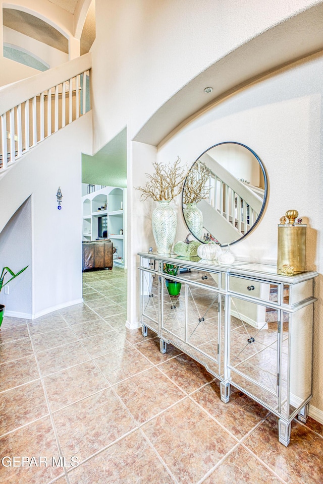 hallway with tile patterned flooring, a towering ceiling, and baseboards