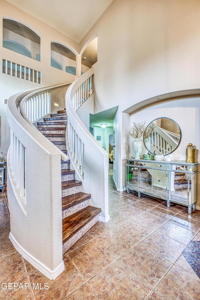 stairs featuring a high ceiling, visible vents, and baseboards