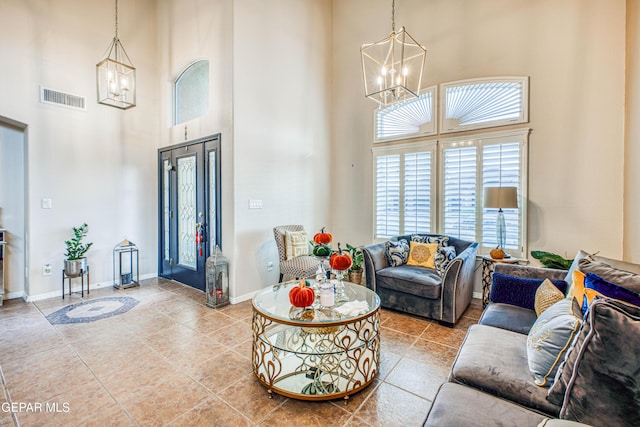 living area featuring a towering ceiling, visible vents, and an inviting chandelier