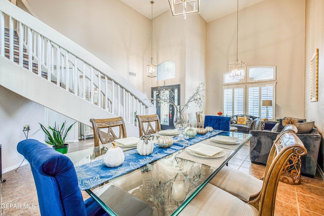 dining area with baseboards, a towering ceiling, tile patterned floors, an inviting chandelier, and stairs