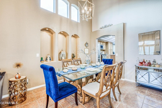 dining room with arched walkways, a notable chandelier, a high ceiling, baseboards, and tile patterned floors