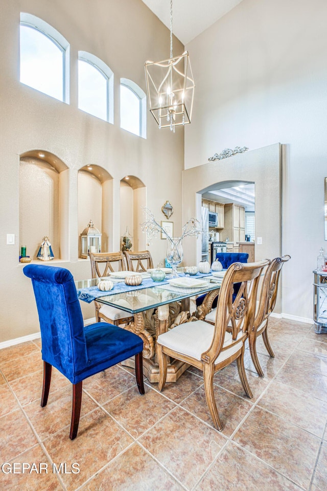 dining area with arched walkways, a notable chandelier, a high ceiling, baseboards, and tile patterned floors