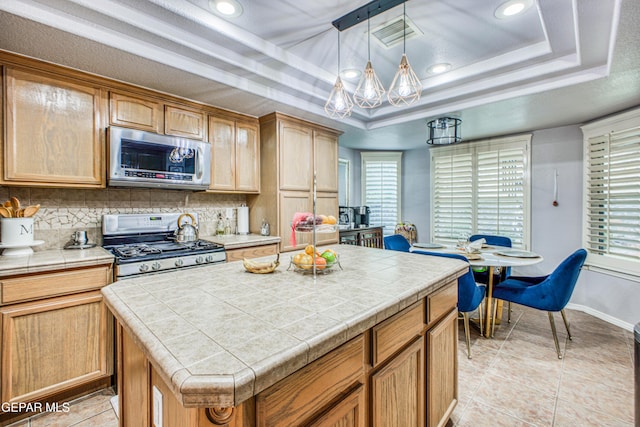 kitchen featuring visible vents, appliances with stainless steel finishes, backsplash, tile counters, and a tray ceiling