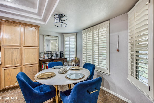 tiled dining area with a textured ceiling and baseboards