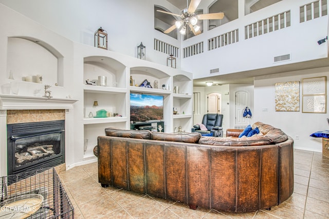 living area with tile patterned flooring, a tiled fireplace, visible vents, and built in features