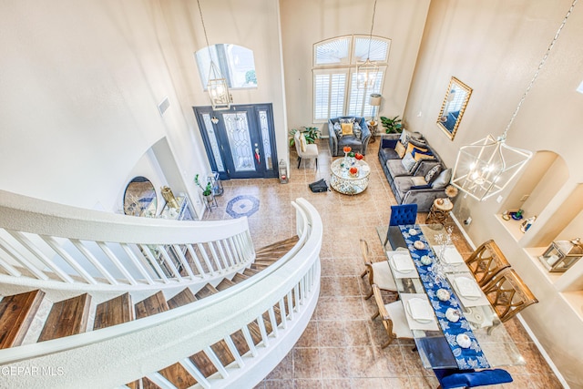 tiled entrance foyer featuring an inviting chandelier, a high ceiling, and visible vents