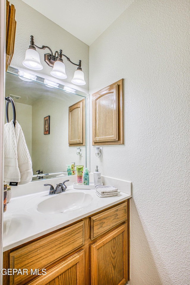 bathroom featuring a textured wall and vanity