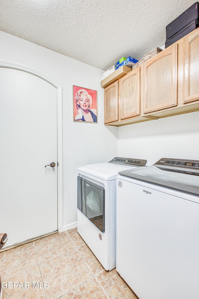 washroom with cabinet space, independent washer and dryer, a textured ceiling, and light tile patterned flooring