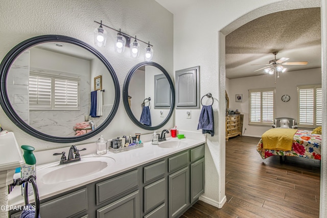 ensuite bathroom with connected bathroom, a sink, a textured ceiling, and wood finished floors