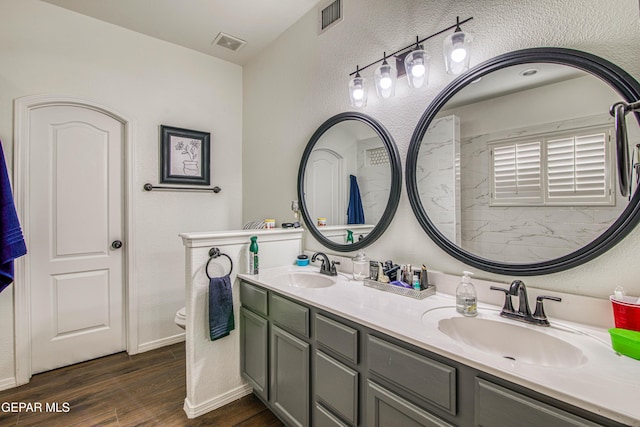 full bath with visible vents, a sink, and wood finished floors