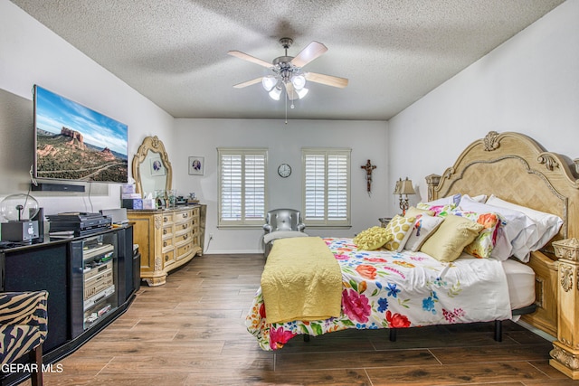 bedroom featuring ceiling fan, a textured ceiling, baseboards, and wood finished floors