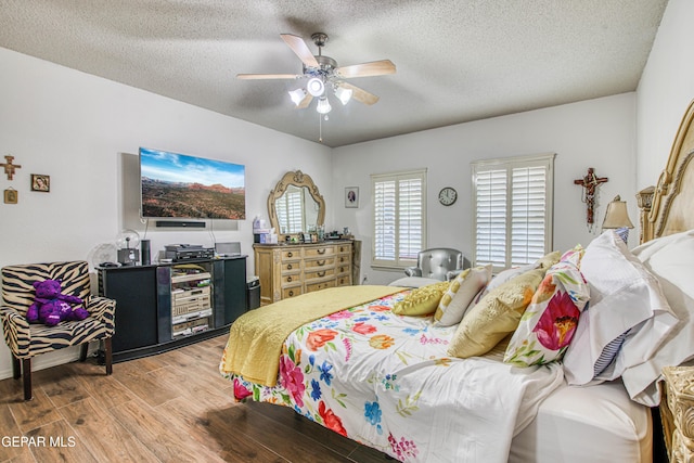 bedroom with a ceiling fan, a textured ceiling, and wood finished floors