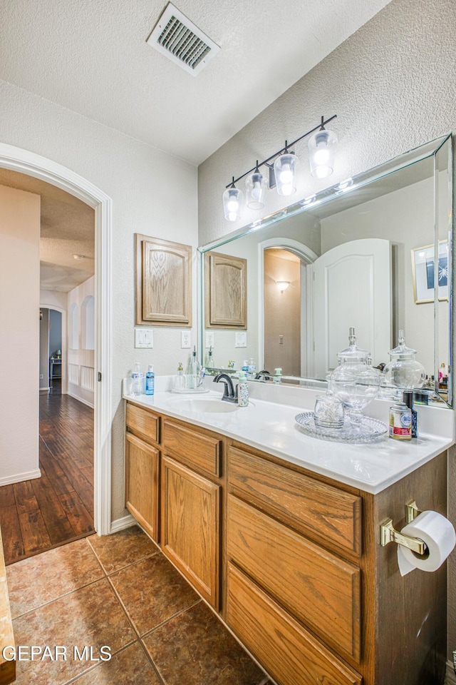 bathroom featuring a textured ceiling, vanity, tile patterned flooring, and visible vents