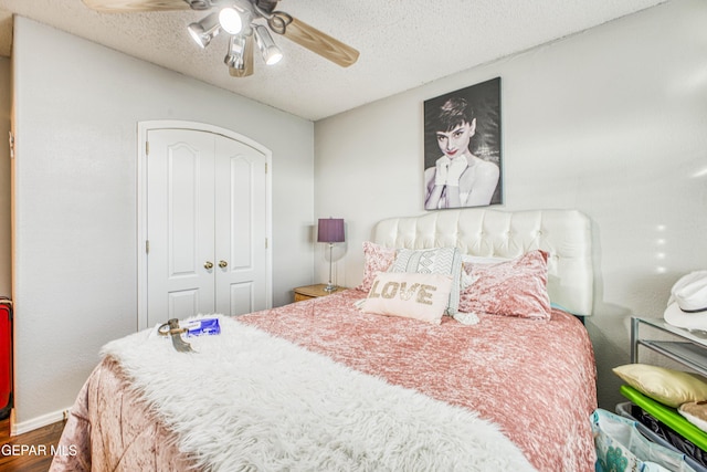 bedroom with a textured ceiling, a closet, wood finished floors, and a ceiling fan