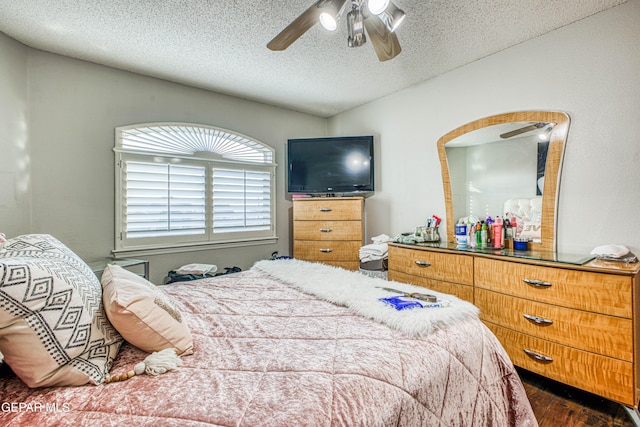 bedroom with dark wood-type flooring, ceiling fan, and a textured ceiling