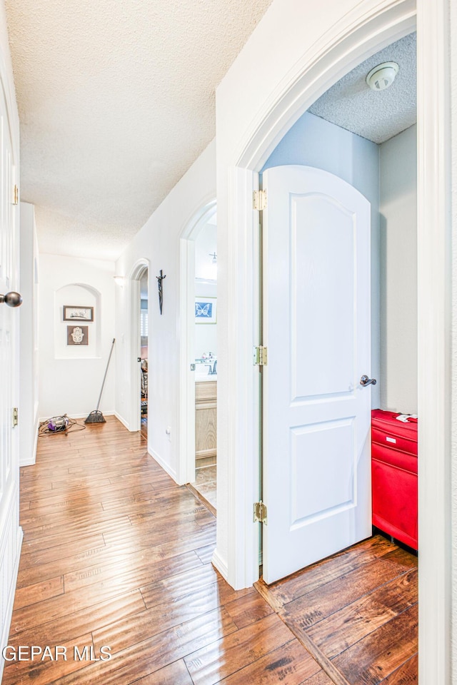 foyer entrance featuring arched walkways, a textured ceiling, and hardwood / wood-style floors