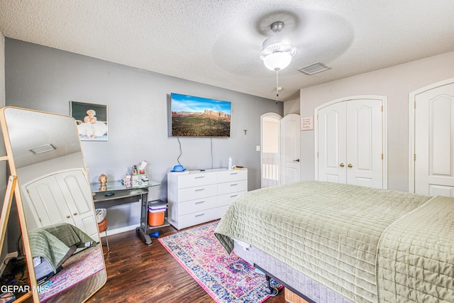 bedroom featuring a textured ceiling, ceiling fan, dark wood-type flooring, and visible vents