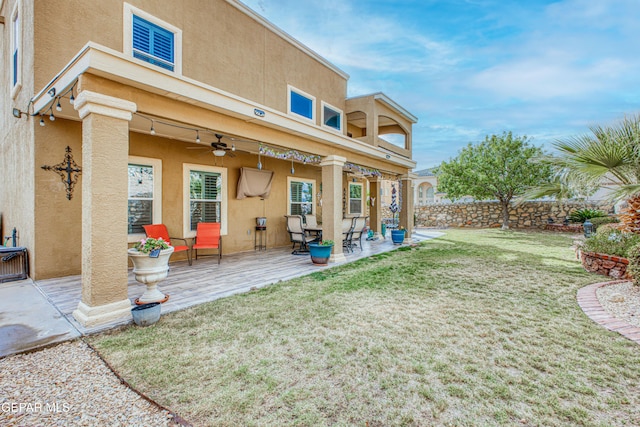 back of house with a yard, ceiling fan, a patio, and stucco siding