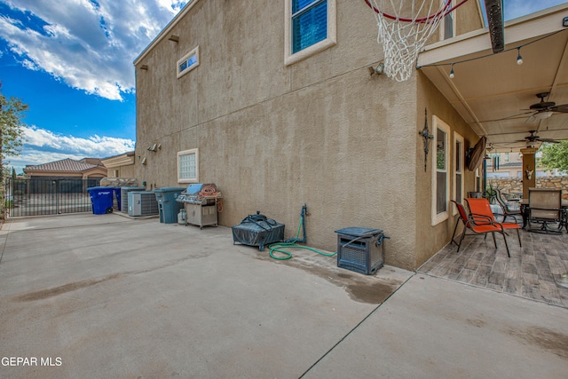 view of property exterior with ceiling fan, fence, a patio, and stucco siding