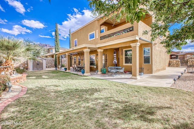 back of property featuring an outdoor structure, a lawn, stucco siding, a shed, and a patio area